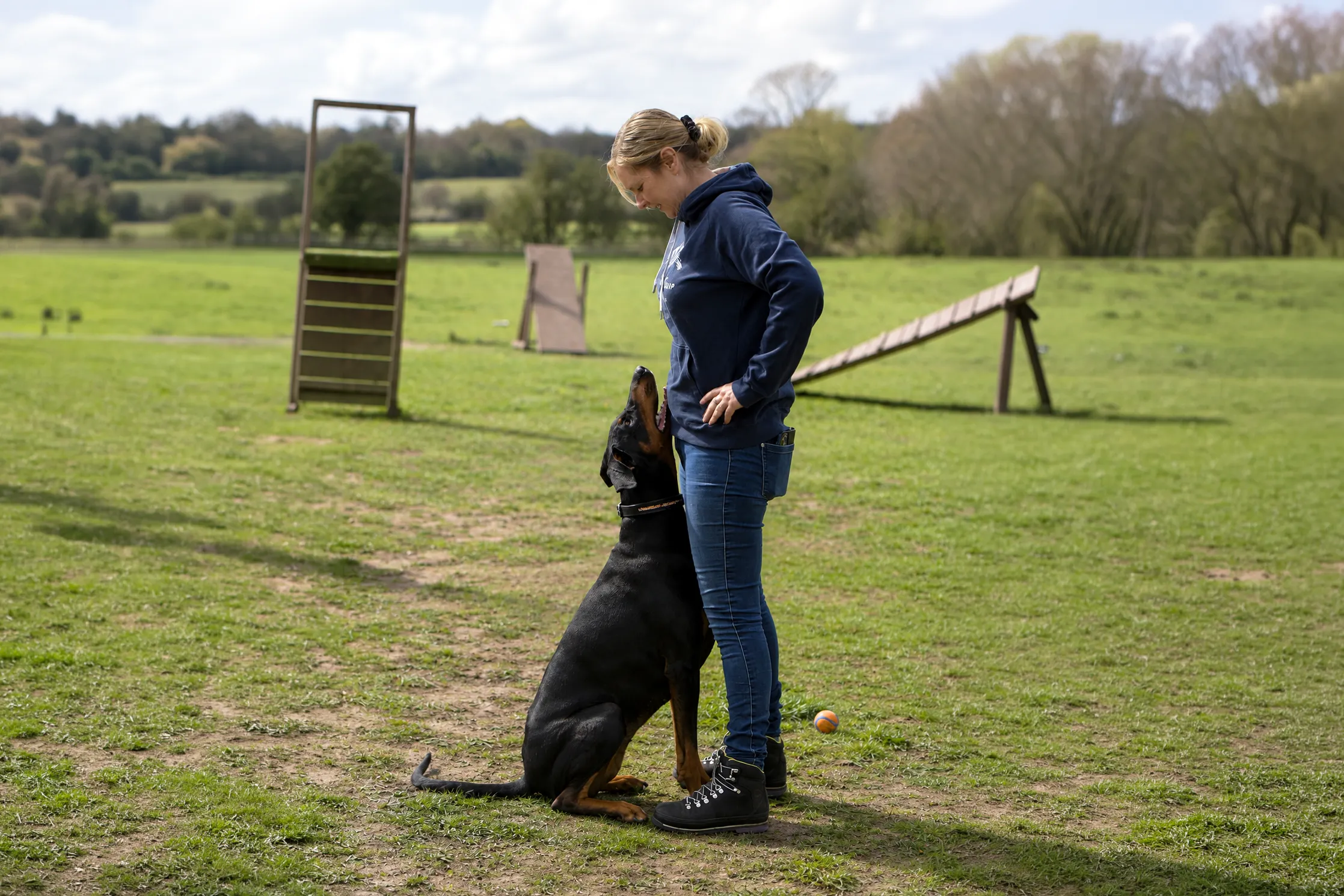 Dog sitting beside a handler during an outdoor training session
